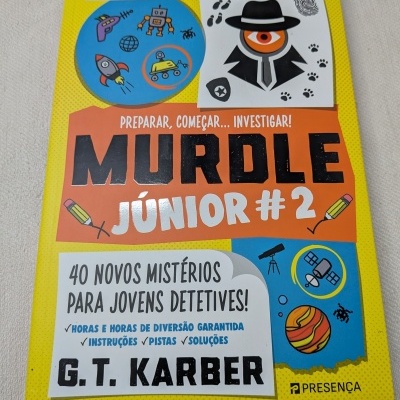 Capa de livro infantil Murdle Júnior #2 em amarelo, laranja e azul com texto e ilustrações.
