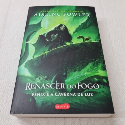 Capa do livro 'Renascer do Fogo Fénix e a Caverna de Luz' com ilustração verde e personagem feminina.
