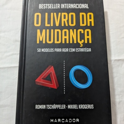 Capa de livro preta com texto amarelo e branco e formas geométricas vermelha e azul