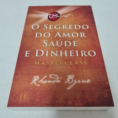 Livro 'O Segredo do Amor Saúde e Dinheiro' de Rhonda Byrne com capa castanha