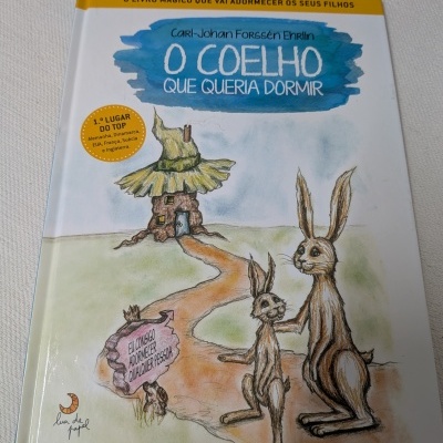 Capa de livro infantil em português com ilustração de lebres e casa de campo
