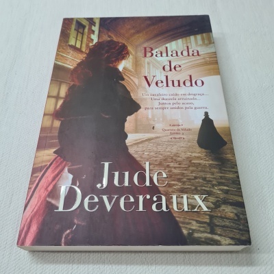 Livro Balada de Veludo de Jude Deveraux com capa ilustrada de mulher com vestido vermelho e xale preto em cenário antigo