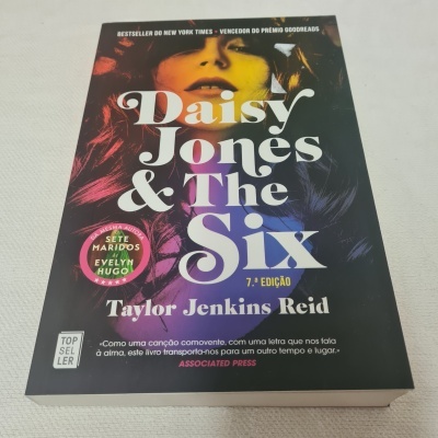 Capa do livro Daisy Jones & The Six com rosto ao fundo e texto colorido.