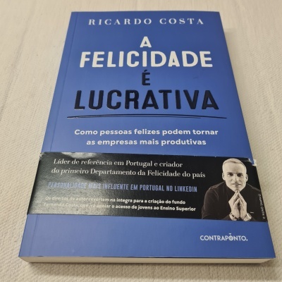 Livro 'A Felicidade é Lucrativa' de capa azul com faixa preta e foto de homem