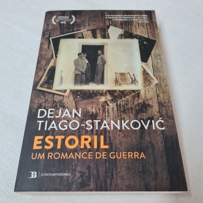 Capa do livro Estoril um romance de guerra com foto a preto e branco e fundo de madeira