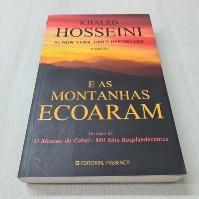Livro com capa em tons laranja e preto intitulado 'E AS MONTANHAS ECOARAM'.
