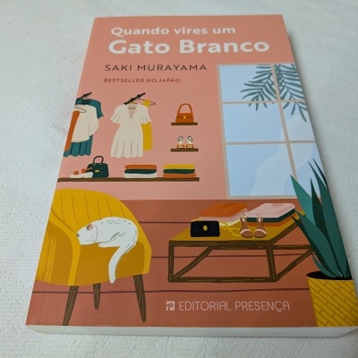 Livro 'Quando vires um Gato Branco' com capa rosa, cadeira amarela e gato branco desenhados.