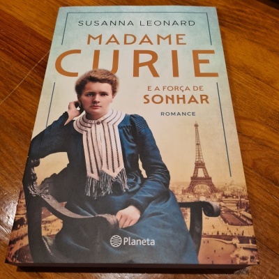 Capa do livro Madame Curie com mulher em traje antigo e Torre Eiffel ao fundo