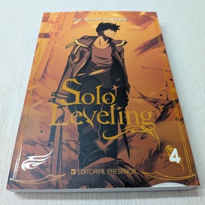 Livro Solo Leveling volume 4 com capa ilustrada em tons de laranja e castanho, personagem masculino com espada