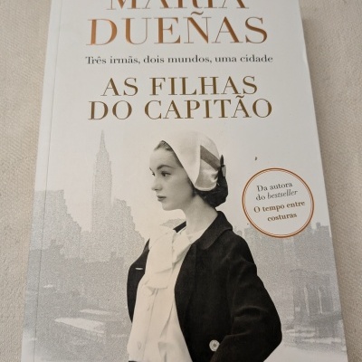 Capa do livro As Filhas do Capitão de María Dueñas, com foto de mulher em preto e branco e texto em dourado e preto.