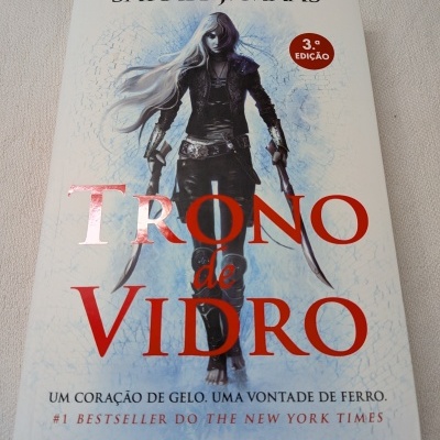 Capa do livro Trono de Vidro de Sarah J. Maas com personagem feminina e texto em português