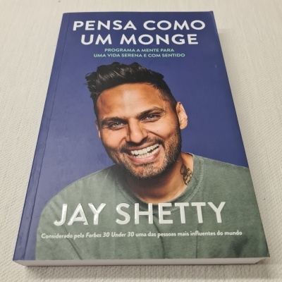 Capa de livro 'Pensa como um monge' de Jay Shetty, com autor sorridente e fundo azul