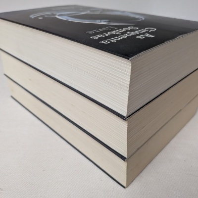 Dois livros com capas pretas e páginas brancas empilhados sobre uma superfície clara