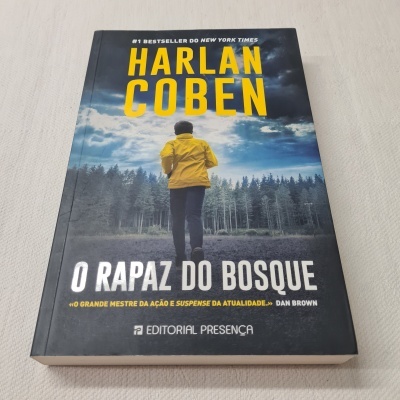 Capa do livro 'O RAPAZ DO BOSQUE' de Harlan Coben com pessoa de casaco amarelo de costas e floresta ao fundo