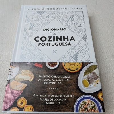 Livro 'Dicionário Prático da Cozinha Portuguesa' com faixa ilustrada e texto promocional.