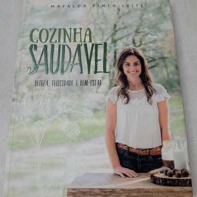 Capa de livro COZINHA SAUDÁVEL com mulher sorridente e mesa de madeira com frascos