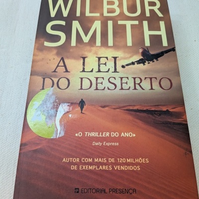 Livro A Lei do Deserto de Wilbur Smith com ilustração de deserto, avião e texto promocional na capa.