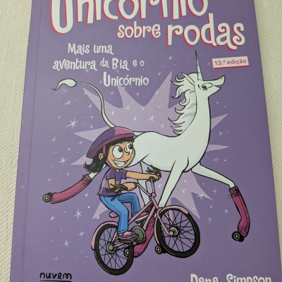 Capa de livro infantil Unicórnio sobre rodas com menina de bicicleta e unicórnio com patins
