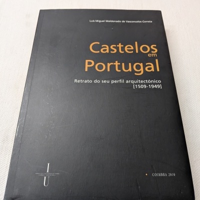 Livro Castelos em Portugal com capa preta e texto em laranja e branco