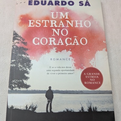 Capa de livro com título Um Estranho no Coração de Eduardo Sá, imagem de pessoa junto a lago