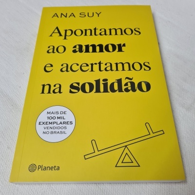 Capa de livro amarela com texto em preto e selo branco sobre fundo branco.