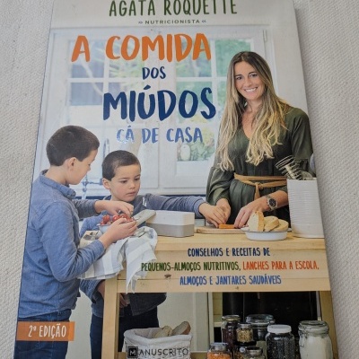 Capa do livro A COMIDA DOS MIÚDOS CÁ DE CASA com mulher e duas crianças a preparar comida numa cozinha.