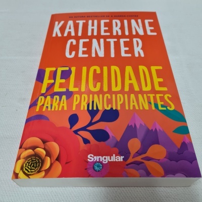 Livro Felicidade Para Principiantes de Katherine Center com capa laranja e flores coloridas