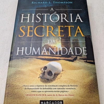 Capa do livro A História Secreta da Humanidade com ilustração de pedras antigas e um crânio na areia.