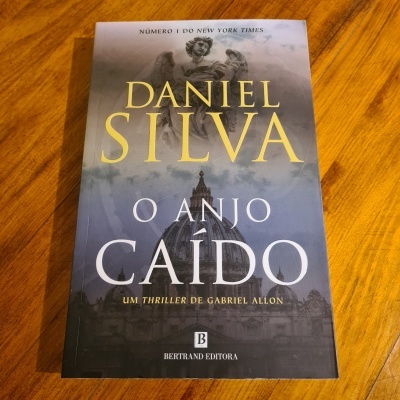 Livro 'O Anjo Caído' de Daniel Silva com estátua de anjo na capa