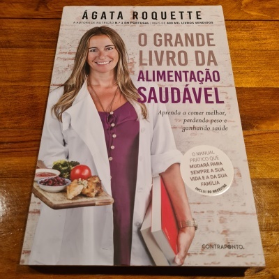 Capa do livro 'O Grande Livro da Alimentação Saudável' de Ágata Roquette com a autora segurando comida e livro.