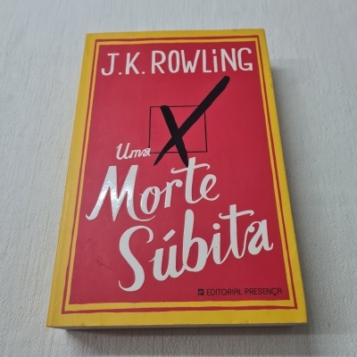 Livro 'Uma Morte Súbita' de J.K. Rowling com capa vermelha e amarela.