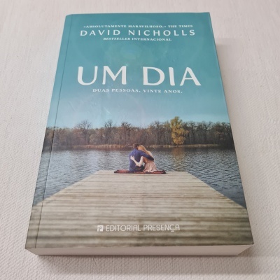 Livro capa dura UM DIA de David Nicholls com imagem de casal num cais junto a lago