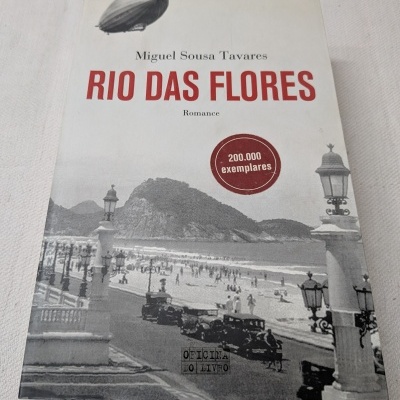 Capa do livro RIO DAS FLORES de Miguel Sousa Tavares com imagem a preto e branco de praia e selo vermelho.