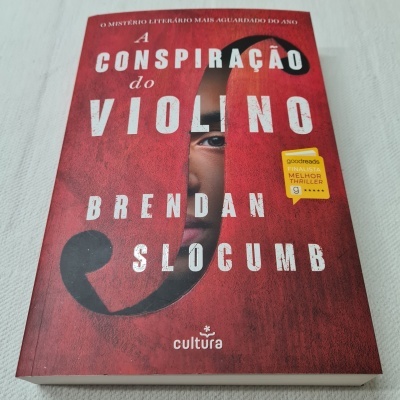 Capa do livro 'A Conspiração do Violino' em vermelho com texto branco e amarelo
