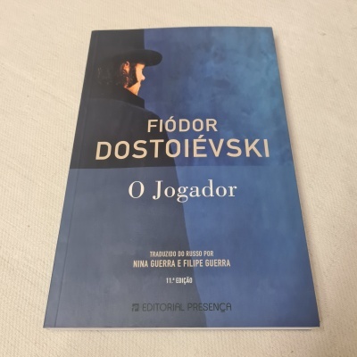 Capa azul de livro O Jogador de Fiódor Dostoiévski com imagem de pessoa de perfil usando chapéu