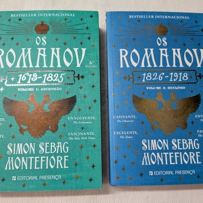 Dois livros Os Romanov de Simon Sebag Montefiore, capas verde e azul, com textos brancos e dourados.