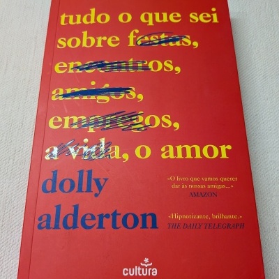 Livro vermelho com texto amarelo e azul e fundo branco texturizado