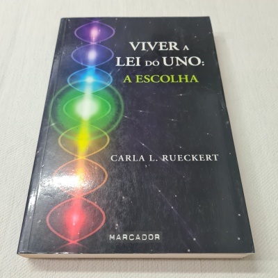Livro 'Viver a Lei do Uno: A Escolha' de Carla L. Rueckert com capa preta e design colorido
