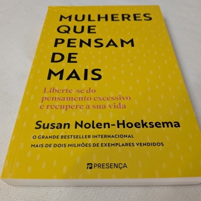 Livro amarelo 'Mulheres que pensam de mais' de Susan Nolen-Hoeksema sobre fundo branco.