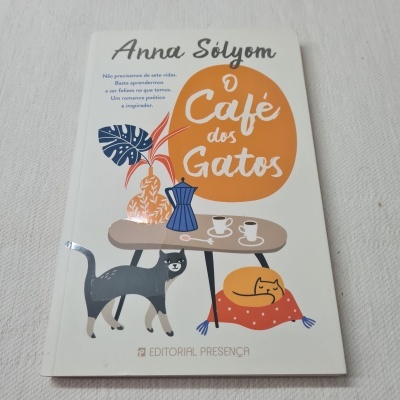 Livro O Café dos Gatos com ilustração de gatos e mesa de café.