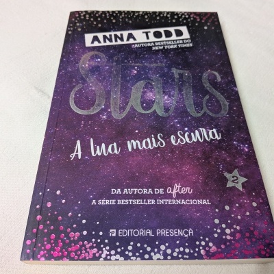Capa do livro Stars A lua mais escura de Anna Todd com padrão de céu estrelado e texto em branco e prateado