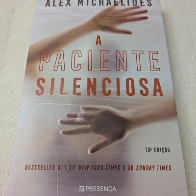 Capa do livro A Paciente Silenciosa com texto e imagem de mãos desfocadas