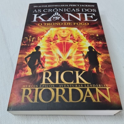 Capa do livro As Crônicas dos Kane: O Trono de Fogo de Rick Riordan com fogo e silhuetas.