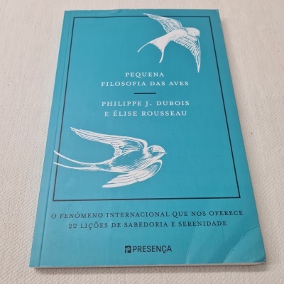 Capa azul de livro com desenhos brancos de pássaros e texto impresso em português