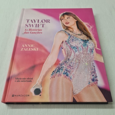 Capa de livro sobre Taylor Swift com texto e imagem da cantora em roupa brilhante.