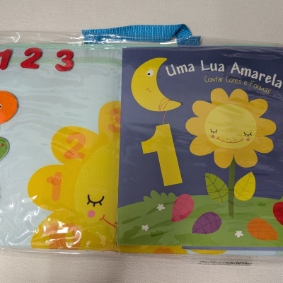 Livro infantil educativo com números e figuras de frutas e flor, embalado em plástico com alça azul.