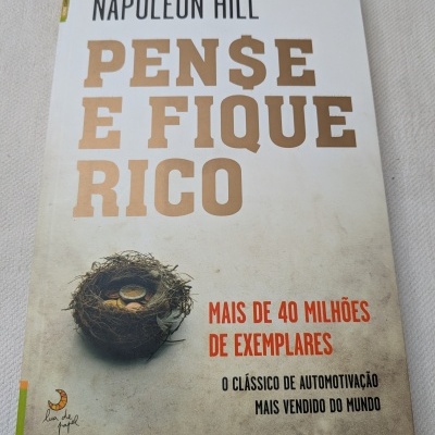 Capa do livro Pense e Fique Rico de Napoleon Hill com ninho e moedas