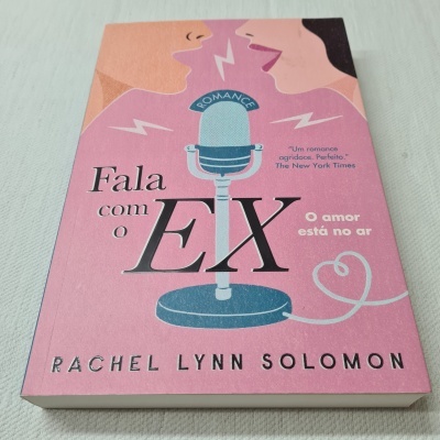Capa de livro rosa com microfone azul e duas pessoas falando, título 'Fala com o EX' de Rachel Lynn Solomon.