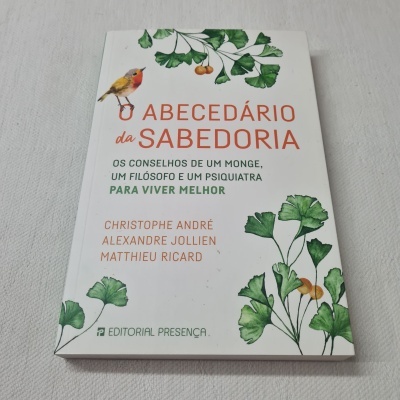 Livro O ABECEDÁRIO da SABEDORIA com folhas verdes e pássaro na capa sobre fundo cinzento claro