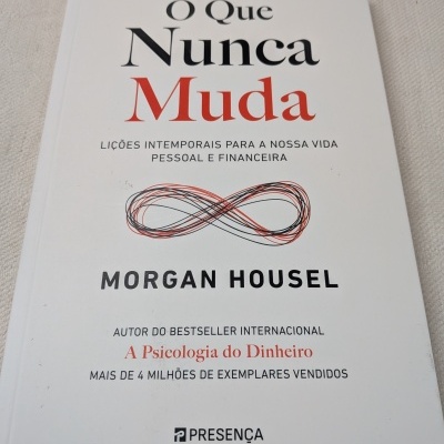 Livro O Que Nunca Muda de capa branca com texto em preto e vermelho
